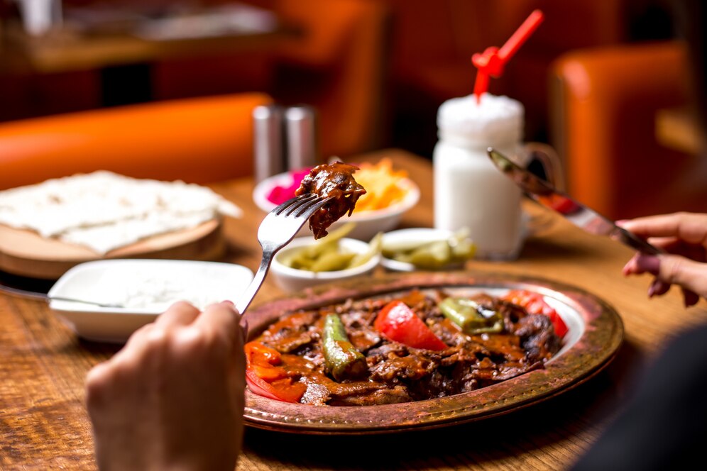 close up woman eating iskender kebab copper platter with pickles yogurt ayran 141793 2082