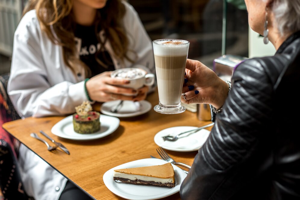 women drinking coffee with desserts cheesecake pistachios cake side view 141793 3221
