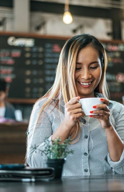 woman-sitting-happily-drinking-coffee-cafe_1150-18784